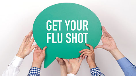 Hands holding a sign reading get your flu shot